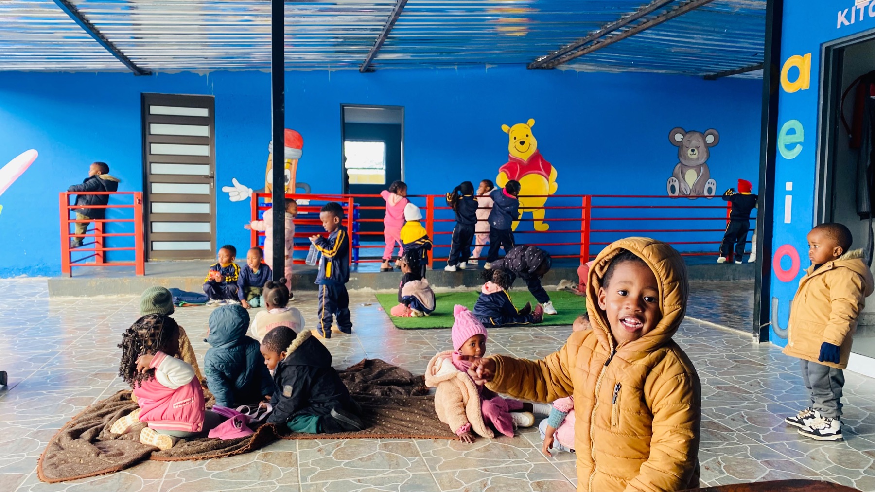 Children playing on the covered veranda beside the Winnie-the-Pooh mural